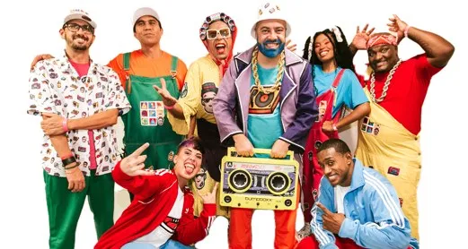 Elenco de AbraKbça com figurinos coloridos e um rádio portátil, em foto de divulgação do Sesc-DF